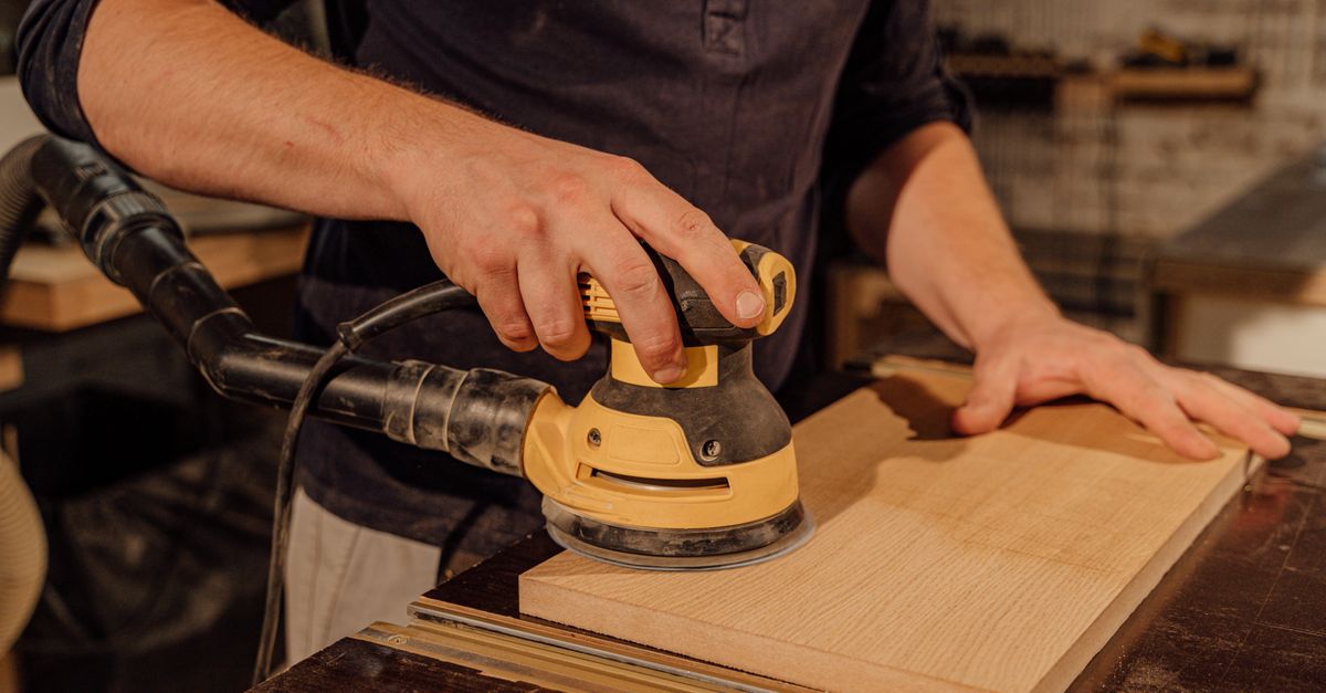 Ponçage d'une pièce de bois avec une ponceuse orbitale dans un atelier