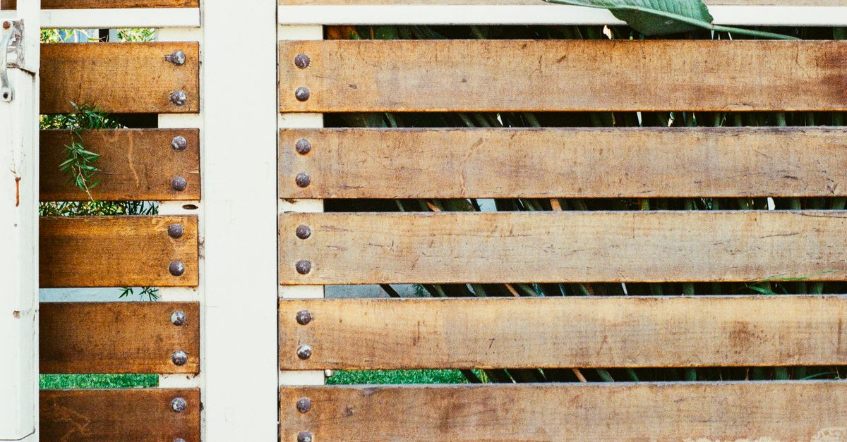 Brise-vue en lames de bois horizontales fixées sur des poteaux dans un jardin