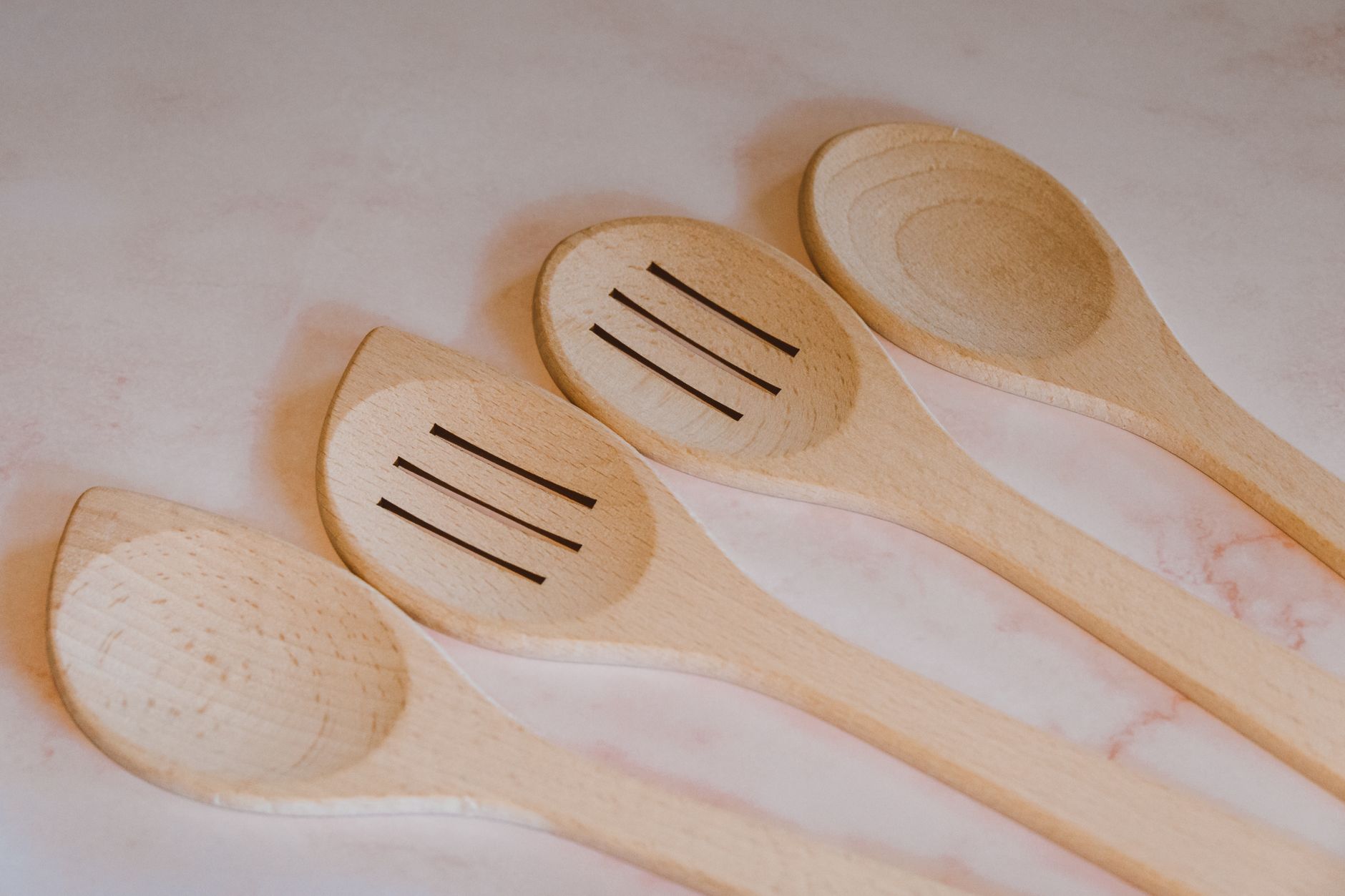 Ustensiles de cuisine en bois de hêtre sur un plan de travail en bois clair