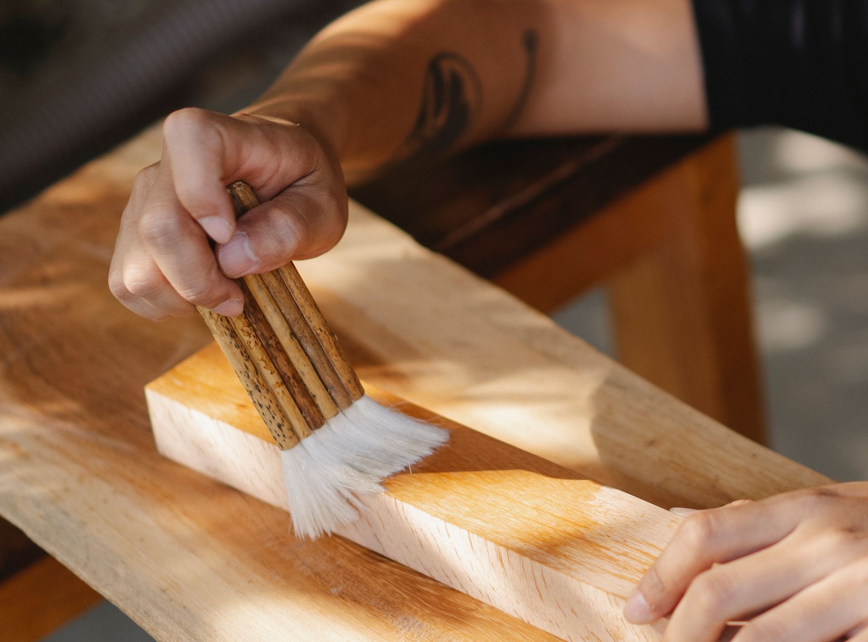 Pinceau plat appliquant un vernis satiné sur un parquet en chêne fraîchement poncé